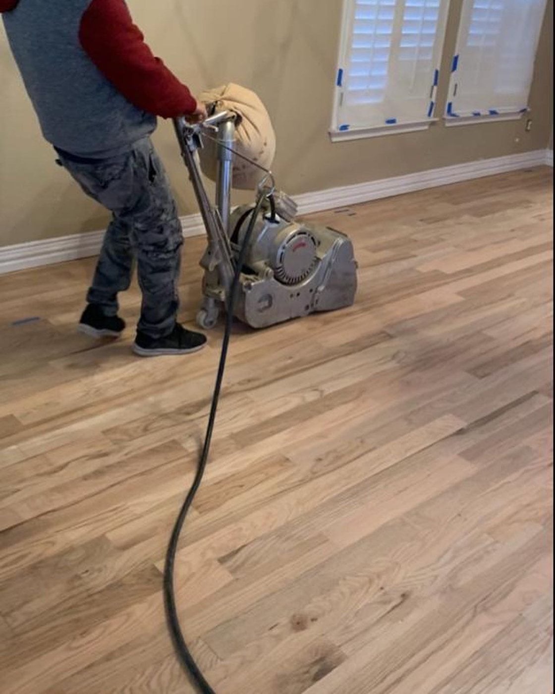 Bernard Hardwood Floors crew sanding a hardwood floor in a Dallas-Fort Worth home (worker actively sanding hardwood floor with equipm)