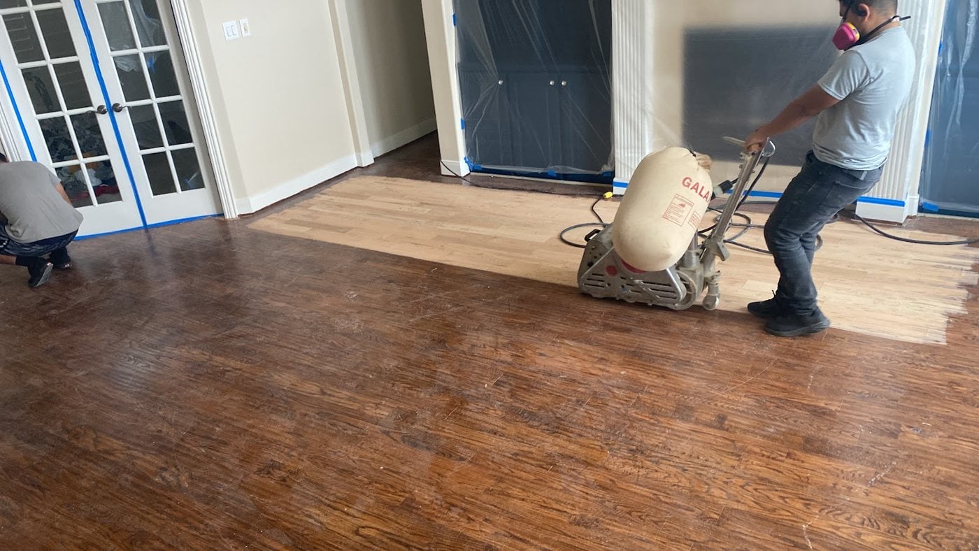 Bernard Hardwood Floors crew sanding a hardwood floor in a Dallas-Fort Worth home (worker actively sanding floor in progress)
