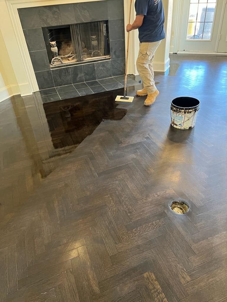 Applying a finish coat to a refinished hardwood floor in a DFW home (worker actively applying finish to floor)
